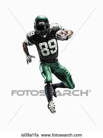 Stock Image - Studio shot of young male football player running with ball. Fotosearch