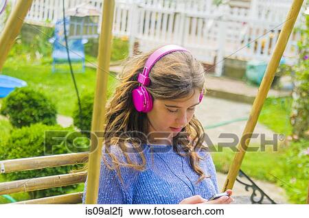 Teenage girl sitting outdoors, wearing headphones View Large Photo Image Stock Image - Teenage girl sitting outdoors, wearing headphones. Fotosearch