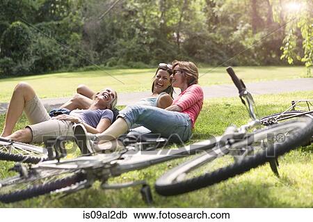 Three mature woman relaxing on grass after bicycle ride View Large Photo Image Stock Image - Three mature woman relaxing on grass after bicycle ride. Fotosearch