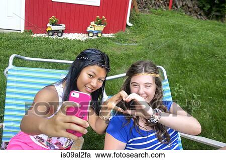 Stock Image - Two teenagers taking self portrait with smartphone. Fotosearch