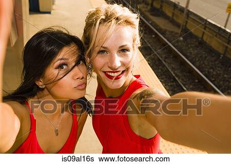 Two young women taking selfie on station platform View Large Photo Image Stock Photograph - Two young women taking selfie on station platform. Fotosearch