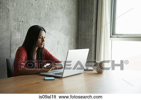 Stock Photograph - Woman using laptop at home. Fotosearch