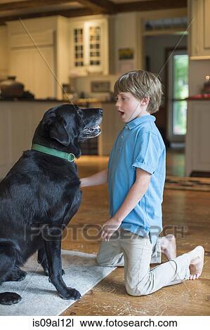 Stock Image - Young boy playing with pet dog. Fotosearch