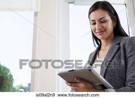 Stock Photo - Young businesswoman woman using digital tablet in office. Fotosearch