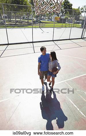 Stock Image - Young couple hugging in basketball court. Fotosearch