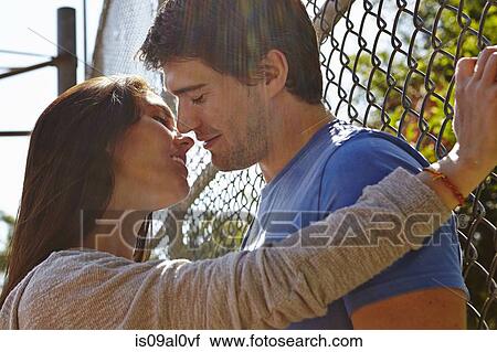 Young couple kissing by wire fence View Large Photo Image Stock Image - Young couple kissing by wire fence. Fotosearch