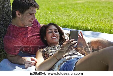 Stock Image - Young couple relaxing in park. Fotosearch