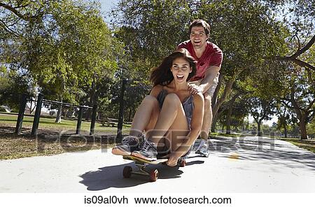 Young couple skateboarding in park View Large Photo Image Stock Image - Young couple skateboarding in park. Fotosearch
