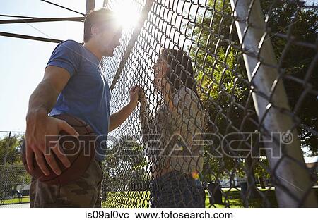 Young couple with basketball standing by wire fence View Large Photo Image Stock Image - Young couple with basketball standing by wire fence. Fotosearch