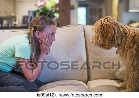 Stock Image - Young girl sitting face to face with pet dog. Fotosearch