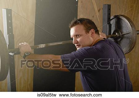 Young male weightlifter preparing to lift barbell in gym View Large Photo Image Stock Photo - Young male weightlifter preparing to lift barbell in gym. Fotosearch