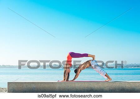 Stock Image - Young man and woman practicing yoga on Pacific beach, San Diego, California, USA. Fotosearch