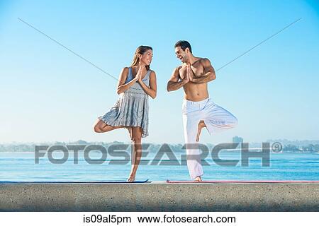 Young man and woman practicing yoga position on pier at Pacific beach, San Diego, California, USA View Large Photo Image Picture - Young man and woman practicing yoga position on pier at Pacific beach, San Diego, California, USA. Fotosearch