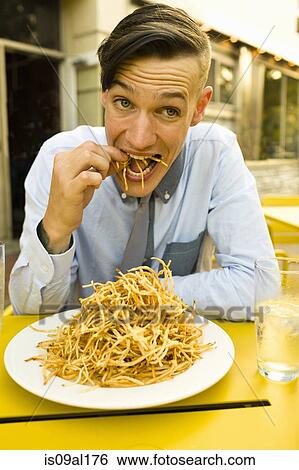 Young man eating skinny french fries at sidewalk cafe View Large Photo Image Stock Photograph - Young man eating skinny french fries at sidewalk cafe. Fotosearch