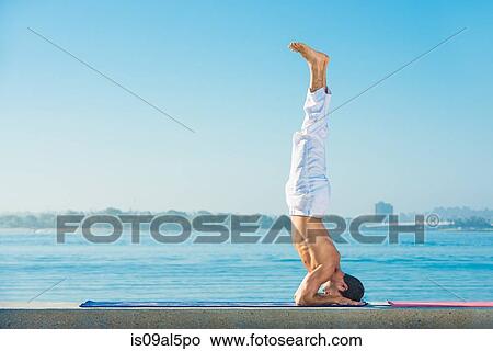 Young man practicing upside down yoga position at Pacific beach, San Diego, California, USA View Large Photo Image Picture - Young man practicing upside down yoga position at Pacific beach, San Diego, California, USA. Fotosearch