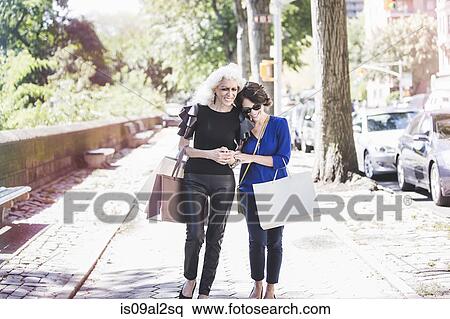 Stock Photography - Young woman and her mentor shopping and laughing on street, New York City, USA. Fotosearch