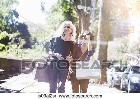 Stock Photography - Young woman and her mentor shopping and laughing on street, New York City, USA. Fotosearch