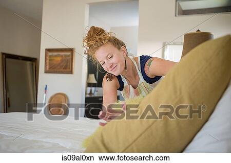 Picture - Young woman cleaning bedroom with green cleaning products. Fotosearch