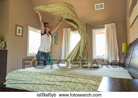 Stock Image - Young woman cleaning bedroom with green cleaning products. Fotosearch
