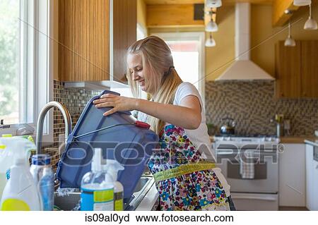 Stock Image - Young woman cleaning kitchen with green cleaning products. Fotosearch