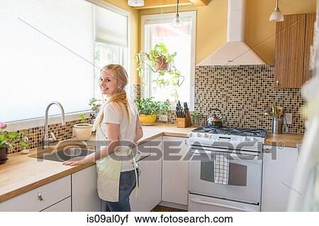 Stock Image - Young woman cleaning kitchen with green cleaning products. Fotosearch