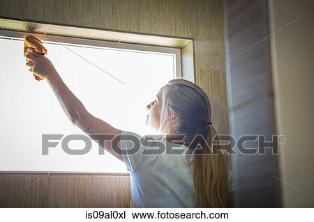 Stock Image - Young woman cleaning window with green cleaning products. Fotosearch