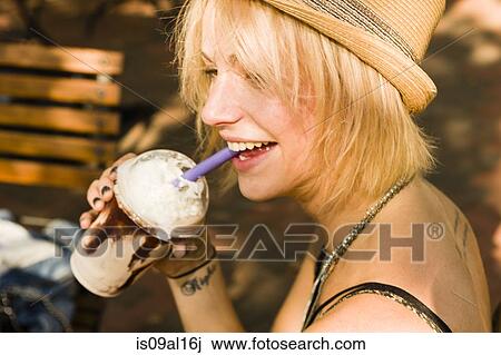 Young woman drinking frappe with a straw in park View Large Photo Image Stock Image - Young woman drinking frappe with a straw in park. Fotosearch