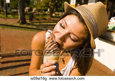 Young woman eating ice cream cone in park View Large Photo Image Stock Image - Young woman eating ice cream cone in park. Fotosearch