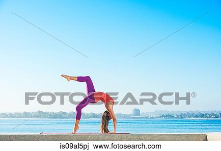 Stock Image - Young woman practicing yoga position at Pacific beach, San Diego, California, USA. Fotosearch