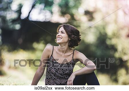 Stock Photo - Young woman relaxing in city park laughing. Fotosearch