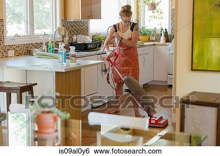 Stock Photograph - Young woman vacuuming with green cleaning products. Fotosearch