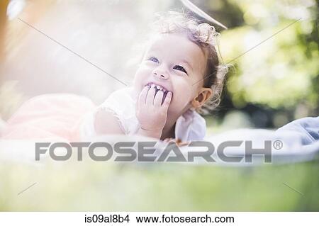 Picture - Baby girl lying on blanket in garden. Fotosearch