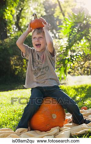Stock Photograph - Boy sitting on pumpkin. Fotosearch