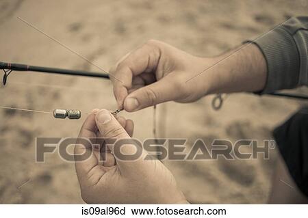 Stock Image - Close up of fishermans hands preparing fishing rod, Truro, Massachusetts, Cape Cod, USA. Fotosearch