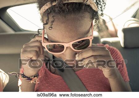 Close up of girl peering though sunglasses on car back seat View Large Photo Image Stock Image - Close up of girl peering though sunglasses on car back seat. Fotosearch