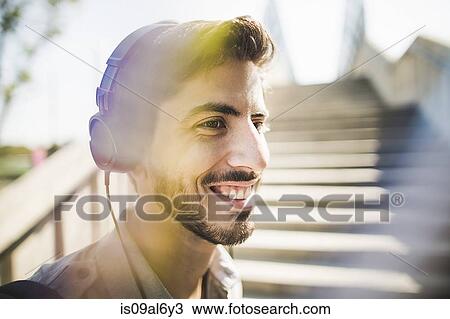 Close up of young man on footbridge listening to music on headphones View Large Photo Image Stock Image - Close up of young man on footbridge listening to music on headphones. Fotosearch