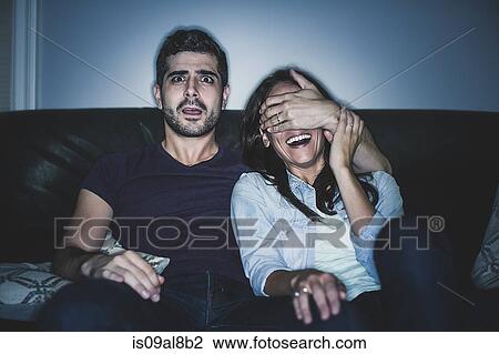 Stock Image - Couple watching thriller on sofa. Fotosearch