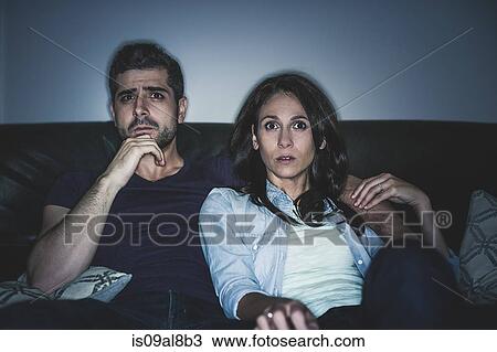 Stock Image - Couple watching thriller on sofa. Fotosearch
