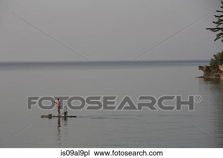 Distant view of teenage boy fishing from paddleboard in Lake Superior, Au Train Bay, Michigan, USA View Large Photo Image Stock Image - Distant view of teenage boy fishing from paddleboard in Lake Superior, Au Train Bay, Michigan, USA. Fotosearch