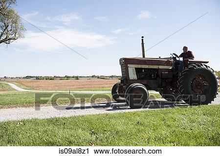 Farmer driving tractor on rural road, Missouri, USA View Large Photo Image Stock Image - Farmer driving tractor on rural road, Missouri, USA. Fotosearch