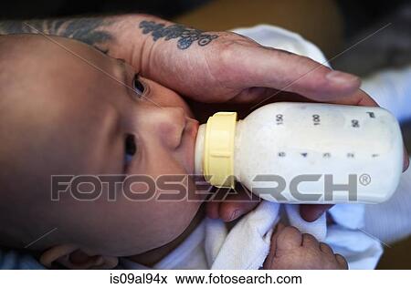 Stock Photo - Fathers hand feeding bottled milk to baby son. Fotosearch