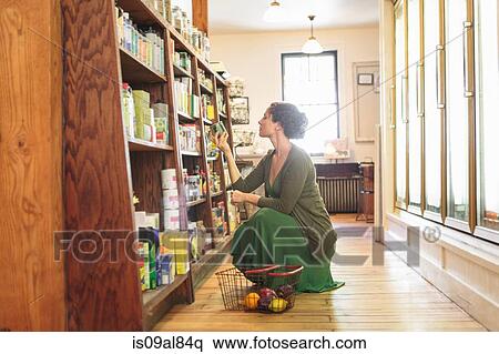 Female customer crouching whilst shopping in country store View Large Photo Image Stock Photography - Female customer crouching whilst shopping in country store. Fotosearch