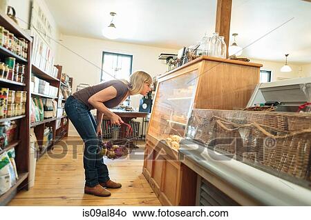 Female customer leaning to look at display cabinet in country store View Large Photo Image Picture - Female customer leaning to look at display cabinet in country store. Fotosearch