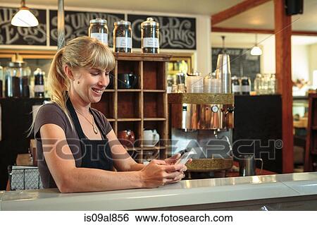 Female shop assistant texting on smartphone in country store cafe View Large Photo Image Stock Photograph - Female shop assistant texting on smartphone in country store cafe. Fotosearch