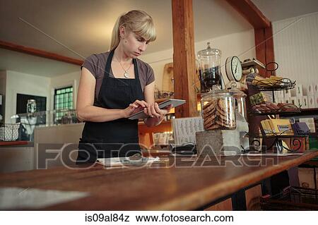 Stock Photo - Female shop assistant using touchscreen on digital tablet in country store. Fotosearch