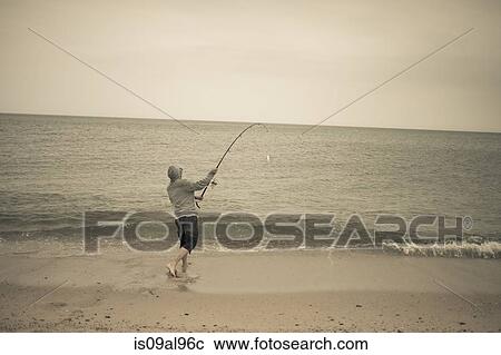 Stock Image - Fisherman casting fishing rod on beach, Truro, Massachusetts, Cape Cod, USA. Fotosearch