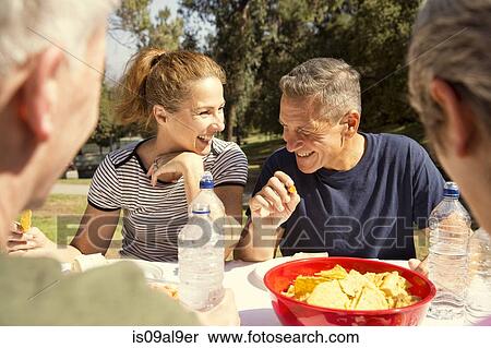 Four mature adult friends chatting over picnic lunch in park View Large Photo Image Stock Photography - Four mature adult friends chatting over picnic lunch in park. Fotosearch