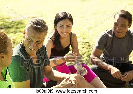 Stock Photo - Four mature male and female runners taking a break in park. Fotosearch