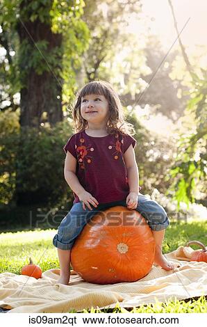 Stock Photograph - Girl sitting on pumpkin. Fotosearch