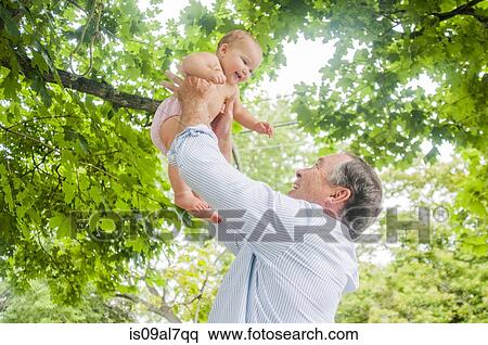 Grandfather lifting up baby granddaughter in park View Large Photo Image Stock Photography - Grandfather lifting up baby granddaughter in park. Fotosearch